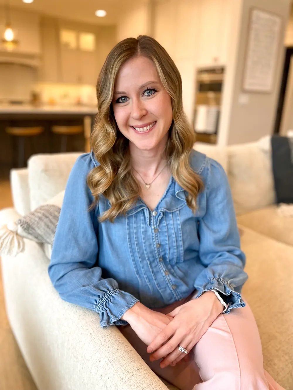 Christine, registered dietitian, smiling on a cream sofa in a denim blouse