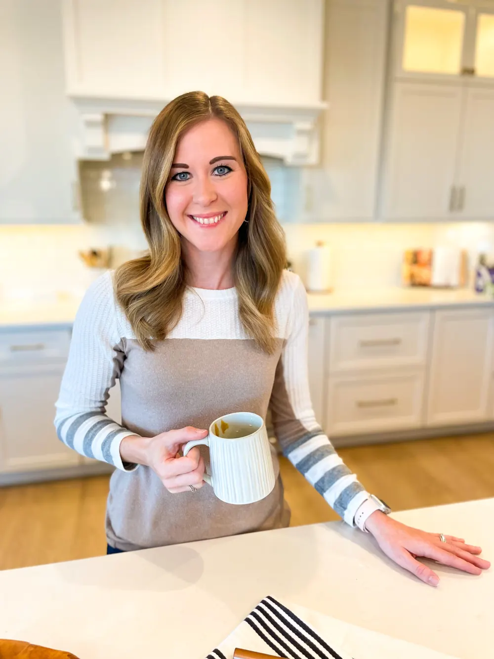 Christine smiling in her kitchen holding a coffee mug