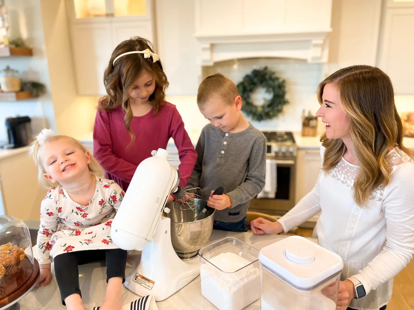 Christine laughing with three young children as they bake together at a kitchen island